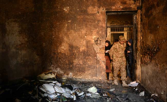 A pakistani soldier shows members of the media a burnt-out classroom, the day after the Taliban attack on a military school (Photo- A Majeed/AFP)