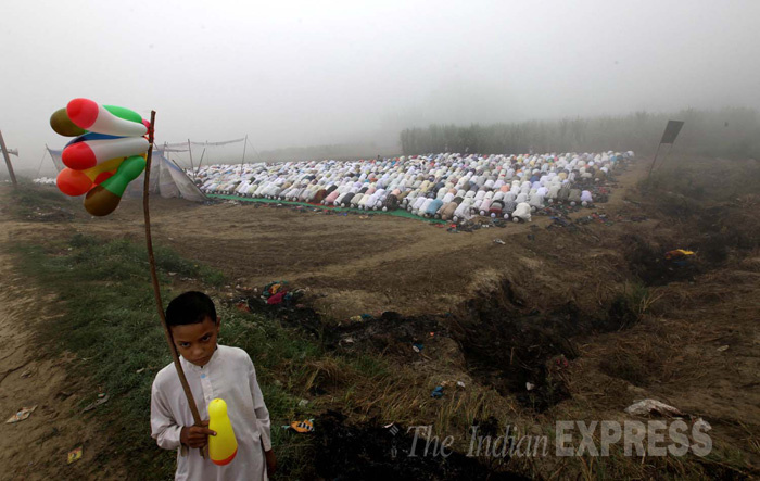 A refugee boy selling balloons as muslim refugees from Muzaffarnagar offer prayers during the Eid celebrations in open at a foggy and cold morning, near the relief camps at Malakpur village in Shamli district, Uttar pradesh (Photo: Ravi Kanojia)