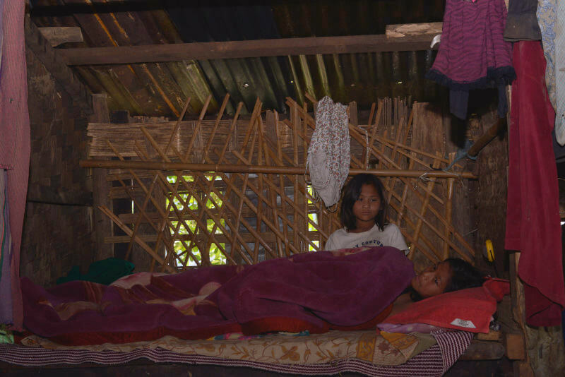 A girl child in a bed and the other one taking care of her